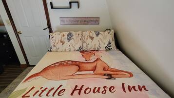 Una cama con estampado floral y el texto 'Little House Inn' en la colcha.