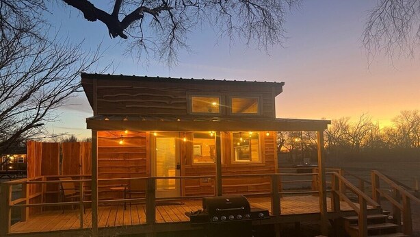 Een houten hut met een terras, een barbecue en een overdekte patio.