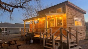 Een houten vakantiehuisje met een veranda, buitenmeubels en een barbecue.