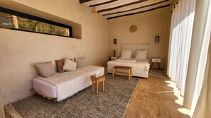 Un dormitorio acogedor con cama, una mesita, un sofá y una ventana con cortinas.