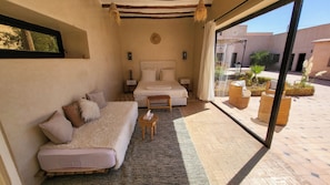 A bedroom with a bed, a sofa, a small table, and a large window. - Tawenza Lodge  (Tamaguert)