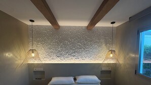 Un dormitorio con una cama, dos lámparas de pared y un ventanal.