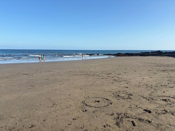 Una playa con huellas y un litoral rocoso.