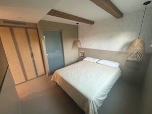 Un dormitorio con cama, armario, puerta y pared con textura.