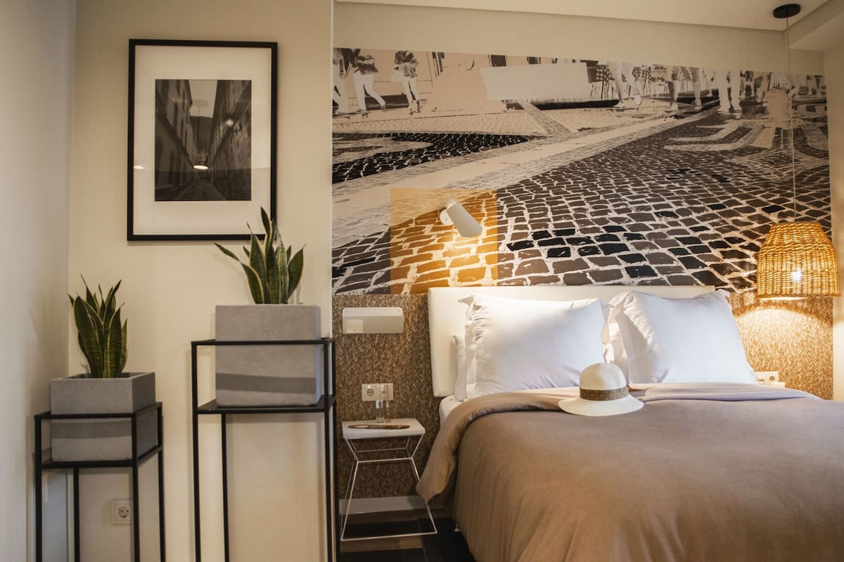 Un dormitorio con una cama, una estantería en la pared, una planta en maceta y una obra de arte.