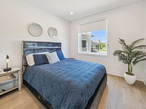 A bedroom with a bed, bedside table, lamp, and a potted plant. - Luxury Resort Villa in Muskoka (Gravenhurst)