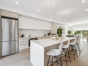A modern kitchen with a large island, stainless steel appliances, and a view to the outside. - Luxury Resort Villa in Muskoka (Gravenhurst)