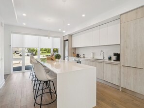 A modern kitchen with a large island, white cabinetry, and a view of the outdoors.