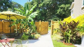 A patio with a table and chairs, a yellow umbrella, and a wooden fence. - Ruby's Cottage / Close to Beaches & Downtown (Mount Pleasant)