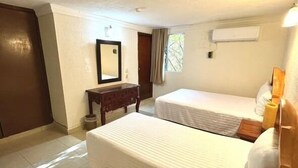 A hotel room with two beds, a wooden dresser, a mirror, and an air conditioning unit. - Explore Cancún Easily | Steps from ADO Bus & Parque Las Palapas | Pool & Garden (Cancun)