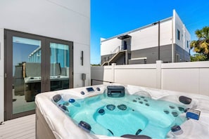 Un jacuzzi sur une terrasse, avec un bâtiment moderne en arrière-plan.