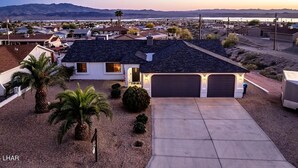 A residential house with a garage, driveway, and a view of a desert landscape with mountains in the background. - The Maverick Sunset Escape (Lake Havasu City)