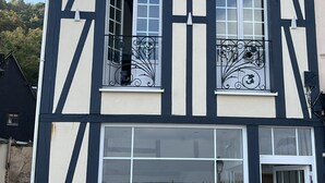 Ein zweistöckiges Gebäude mit einer schwarz-weißen Fachwerkfassade, großen Fenstern und einer Ziegelbasis.