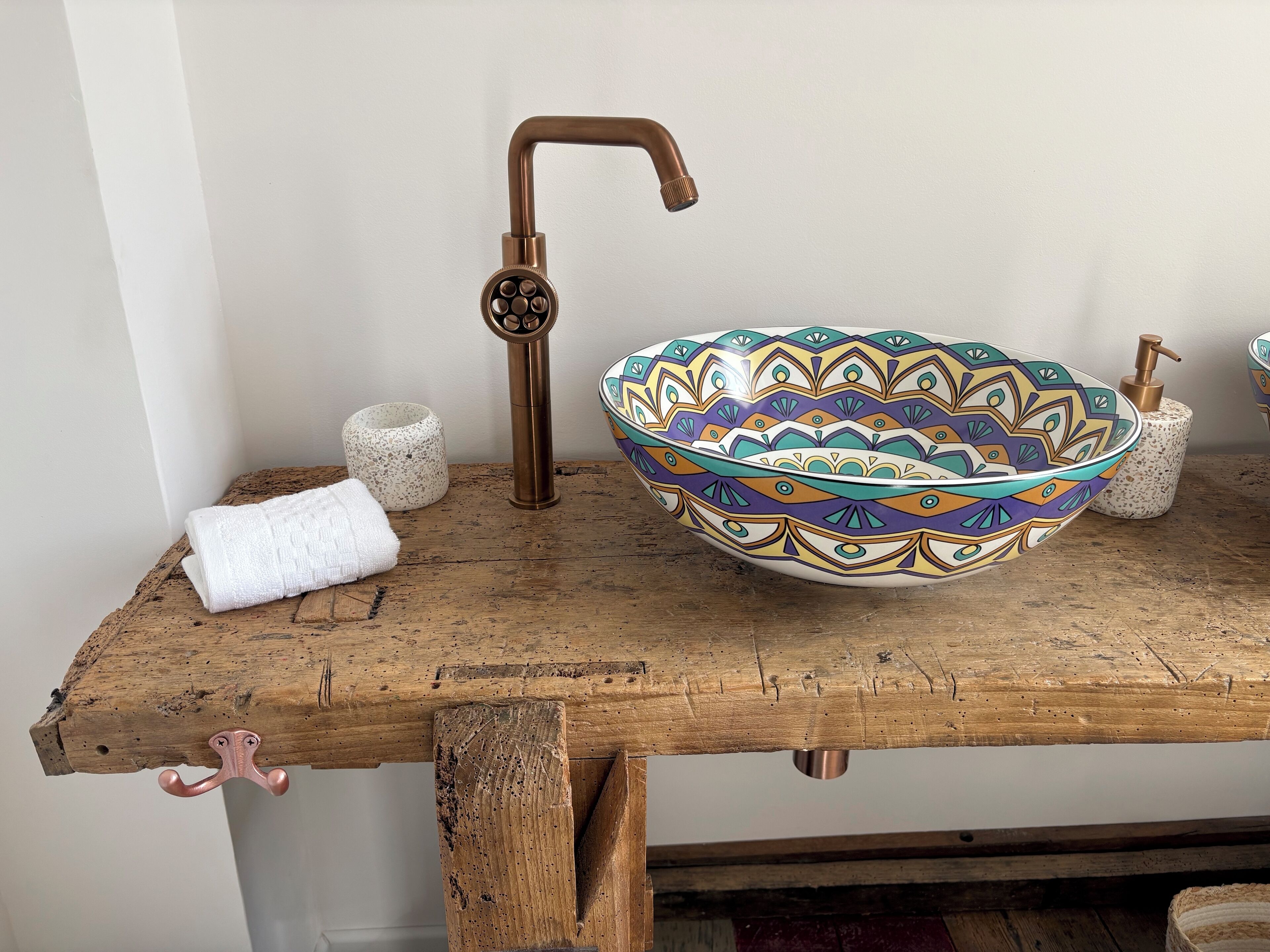 A rustic wooden table with a decorative bowl, a towel, and a soap dispenser.