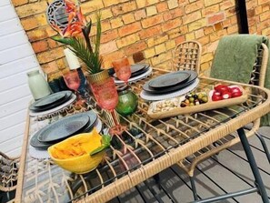 A wicker table with plates, glasses, and a fruit bowl. - Brazenose, Stamford, Lincolnshire. (Lincolnshire)