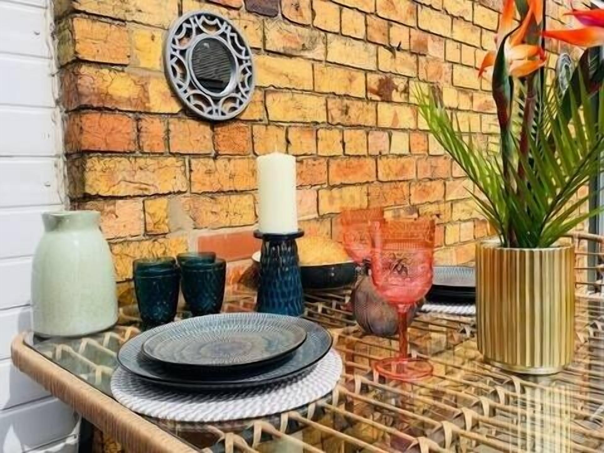 A dining area with a brick wall, a decorative plate rack, and a table with a woven table runner.