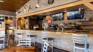 A bar area with a brick wall, wooden ceiling, and multiple seating arrangements.