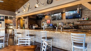 Eine Bar mit Backsteinwand, Holzbalkendecke und verschiedenen Sitzgelegenheiten.