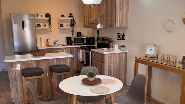 Une cuisine compacte équipée d’un réfrigérateur, d’un four à micro-ondes et d’une cuisinière. Elle comprend également un coin repas avec une table ronde et des chaises.