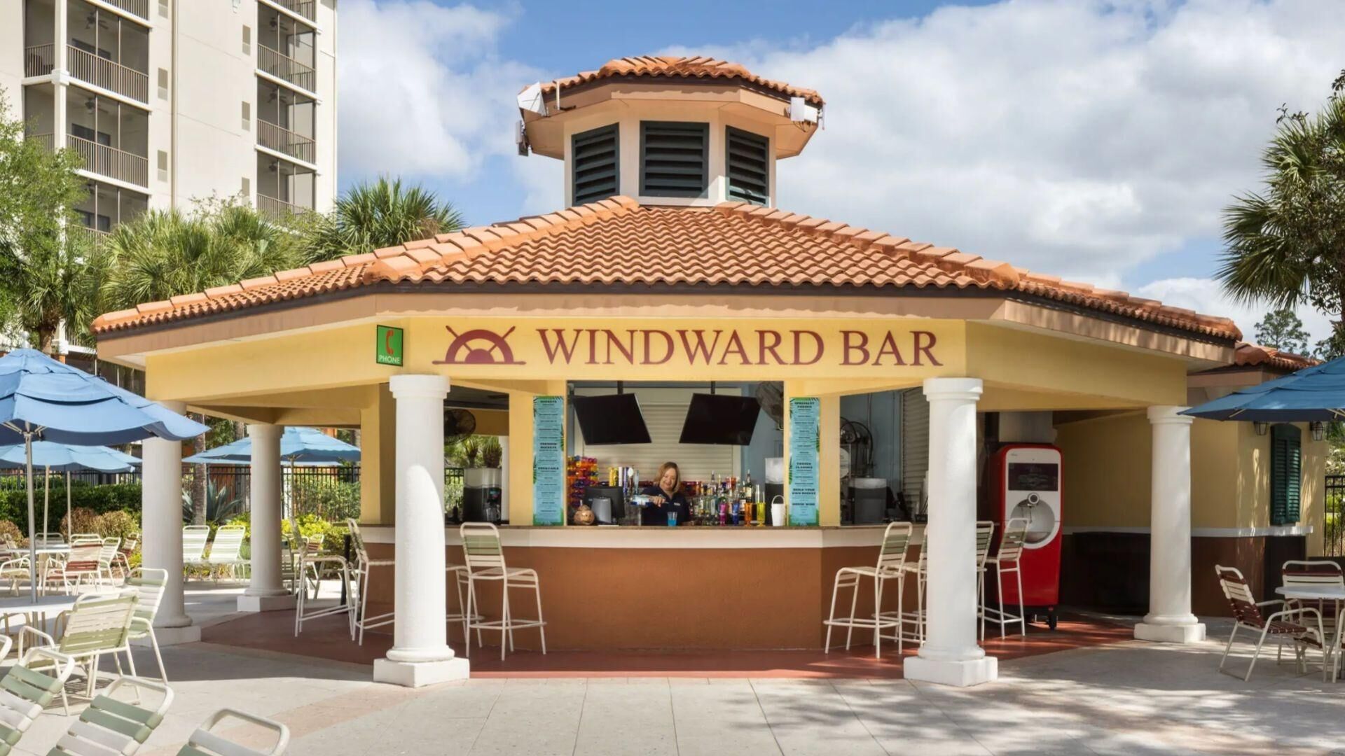 A Windward Bar with a tiled roof, a phone sign, and outdoor seating.