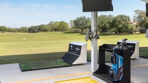 Golfharjoittelualue, jossa on vihreä nurmialue, lyöntialusta ja golfbägi.