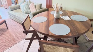 A dining area with a round wooden table, four chairs, a vase with dried plants, and a framed floral artwork on the wall. - Beautiful serenity place (North Myrtle Beach)