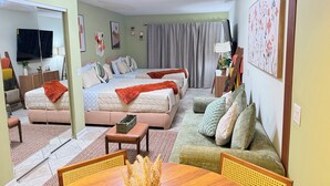 A well-lit hotel room with a large bed, a sofa, a dining table, and a TV. - Beautiful serenity place (North Myrtle Beach)