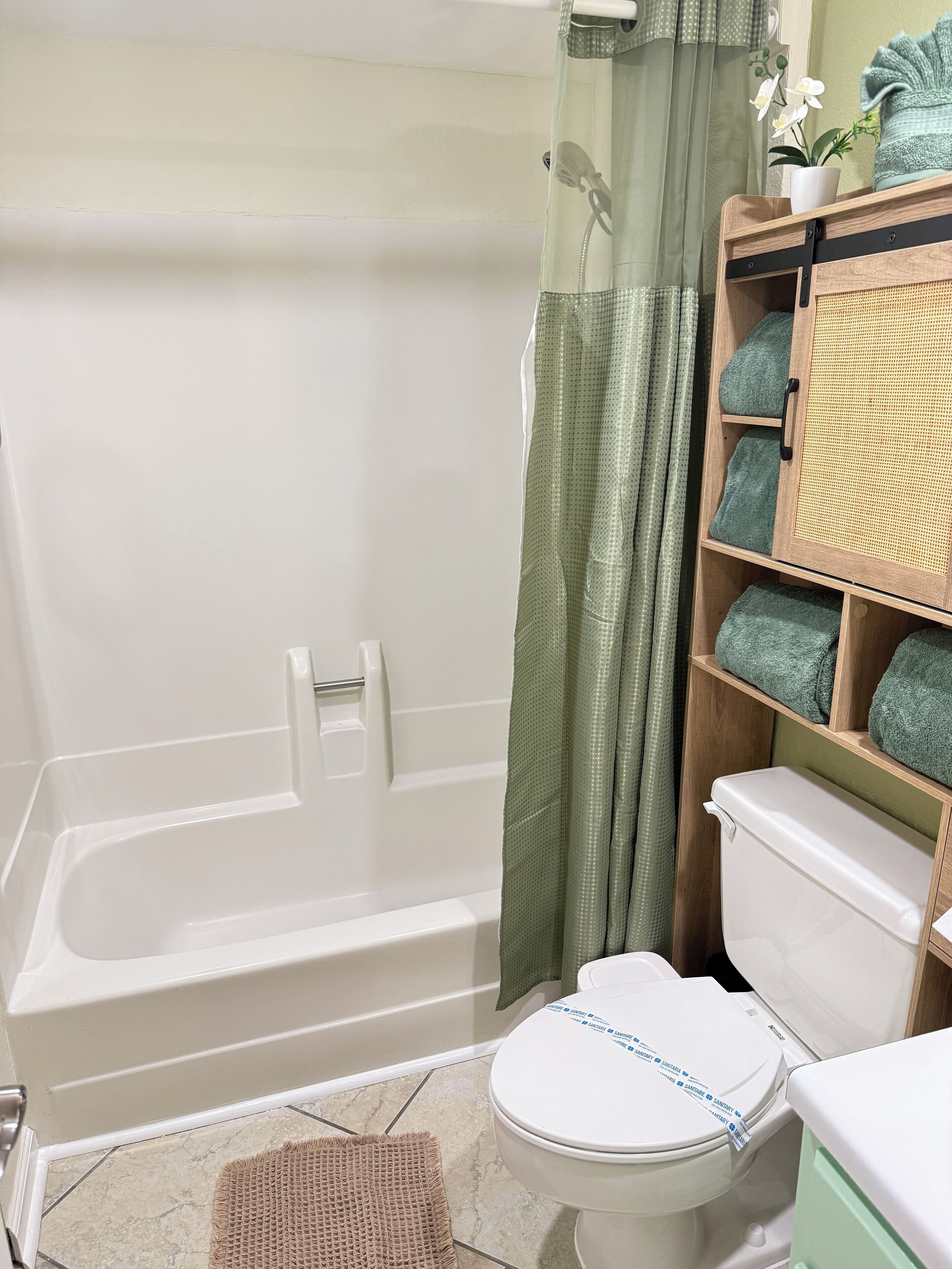 A bathroom with a bathtub, toilet, and a shelf with towels.