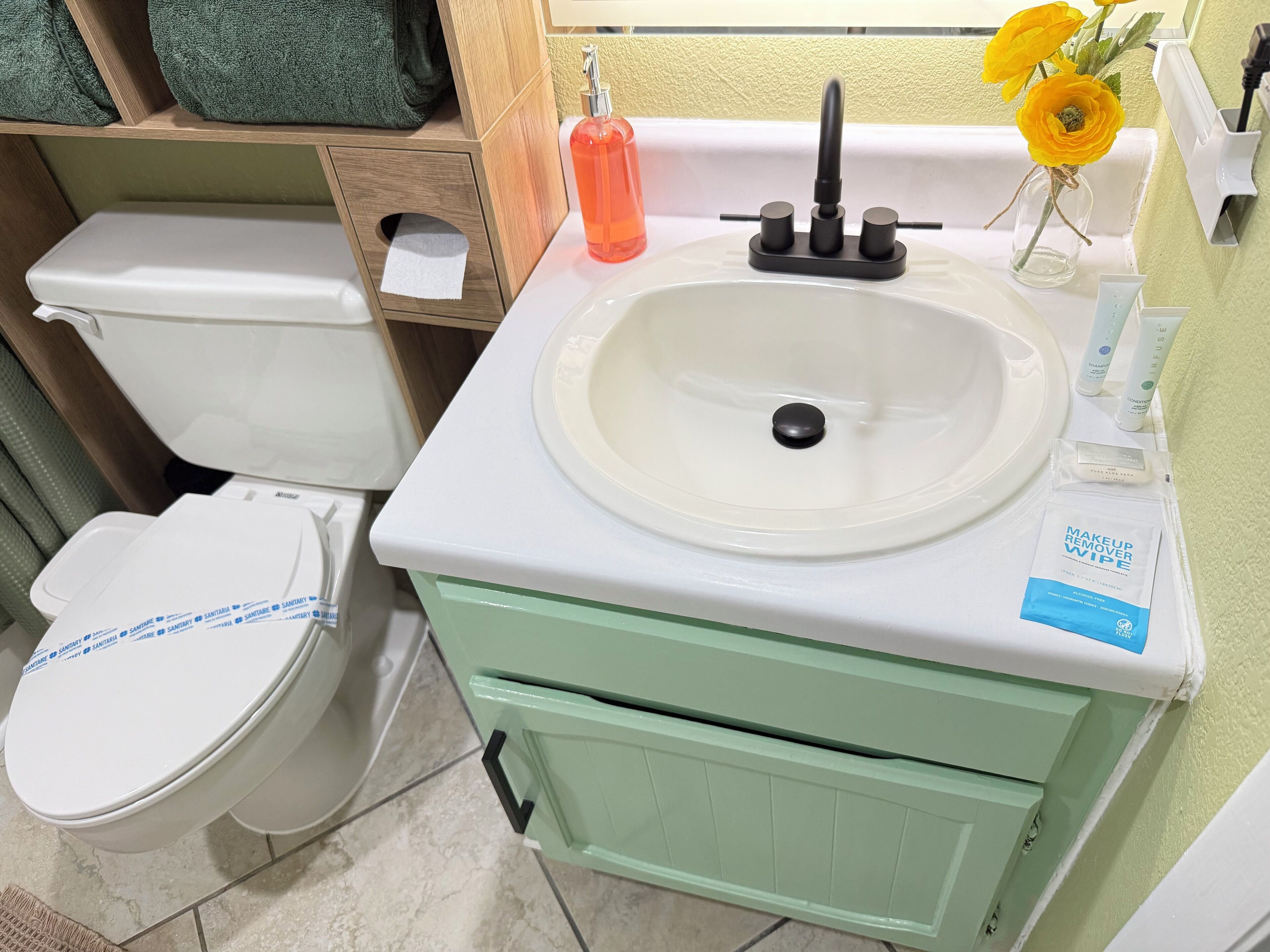 Ein Badezimmer mit Toilette, Waschbecken und einem grünen Schrank.