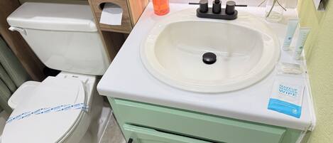 Ein Badezimmer mit Toilette, Waschbecken und einem grünen Schrank.