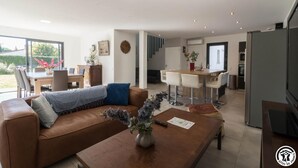A modern living room with a leather sofa, a wooden coffee table, and a dining area with a wooden table and chairs.