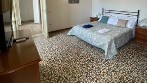 A bedroom with a bed, a wooden dresser, a chandelier, and a tiled floor. - Marini Palace (Spoleto)