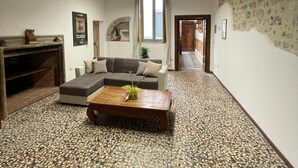 A spacious living room with a large sectional sofa, a wooden coffee table, and a stone-patterned floor. - Marini Palace (Spoleto)