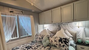 A bedroom with a bed, a nightstand, a ceiling fan, and a window with curtains.