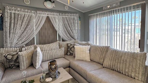 A living room with a beige sectional sofa, a wooden coffee table, and a ceiling fan.