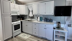 A kitchen with white cabinets, a stove, and a sink.
