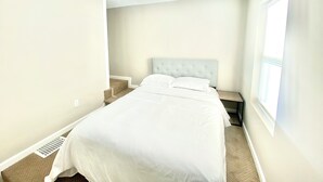 Une chambre à coucher avec un lit, un ventilateur de plafond, une fenêtre et une table de chevet.