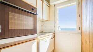 A compact kitchen with a window, a built-in stove, and a dishwasher. - Appartement bord de plage, havre de paix (Ploemeur)