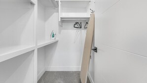 Un petit placard blanc, doté d’étagères, d’une tringle pour suspendre les vêtements et d’une porte.