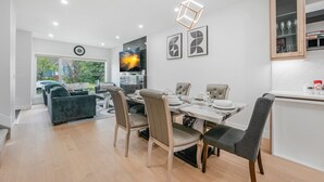 Un espace repas moderne avec une table dressée pour quatre personnes, un canapé et un coin cuisine équipé de placards.