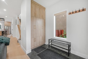 Un intérieur moderne avec une armoire en bois, un banc et une fenêtre donnant sur une clôture rouge.