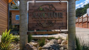 A wooden sign for The Anchor Inn with a clear view of the surrounding area, including a building and a wooden fence. - anchor inn pacifica (Pacifica)