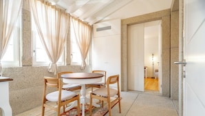 A dining area with a round table and four chairs, a patterned rug, and a stone-textured wall. - Villa T5 - Pool - Casa da Brêa Viana do Castelo (Santa Marta de Portuzelo)