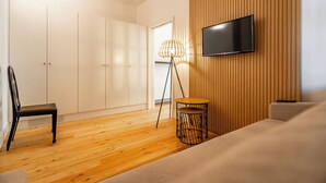 A modern living room with a wooden floor, a sofa, a TV mounted on the wall, a floor lamp, and a wardrobe. - Villa T5 - Pool - Casa da Brêa Viana do Castelo (Santa Marta de Portuzelo)