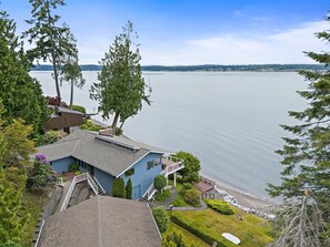 Une maison avec vue sur une vaste étendue d’eau, un quai et un petit bateau.