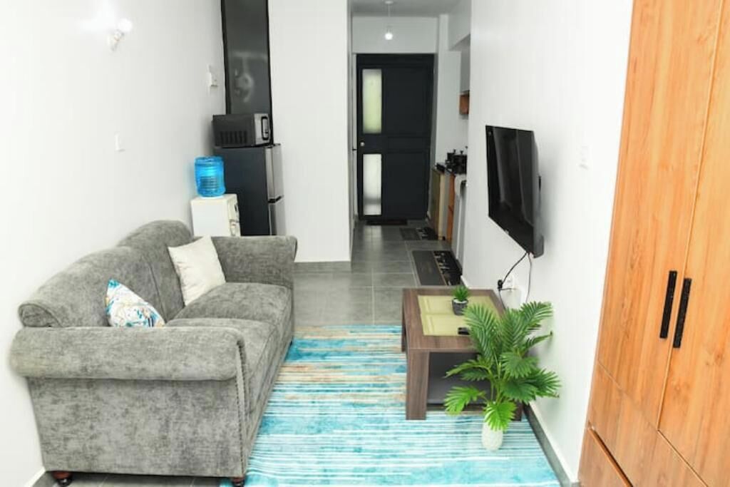A living room with a grey sofa, a coffee table, a TV, and a wooden cabinet.