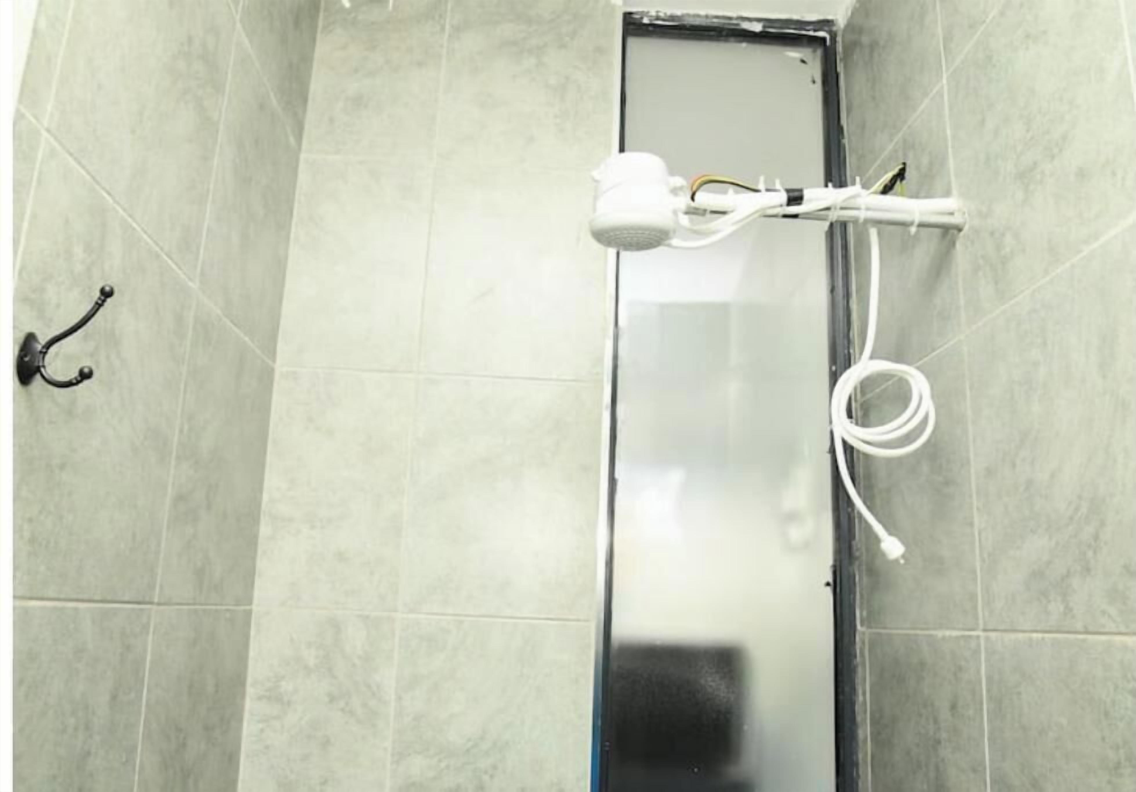 Une salle de bain avec un espace douche, un porte-serviettes et une prise électrique visible.