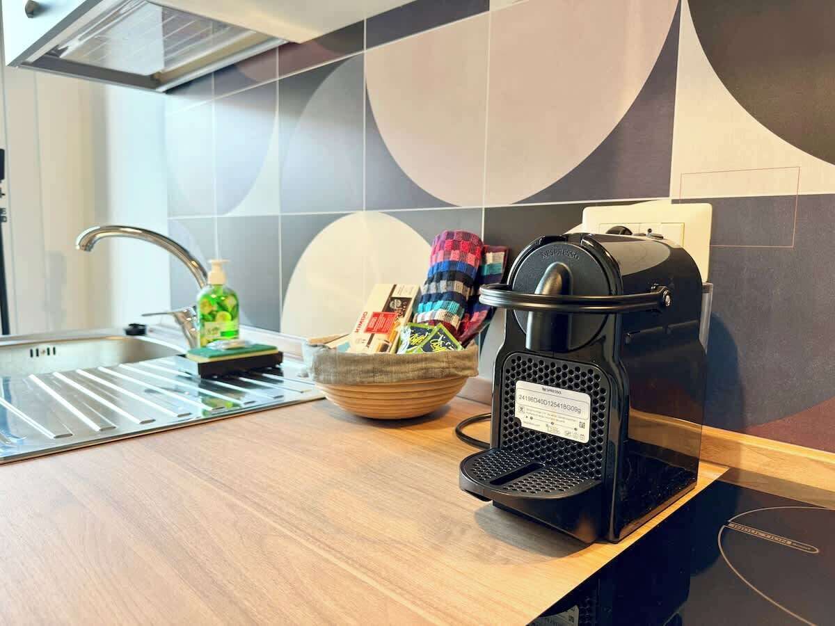 A modern kitchen with a coffee machine, a bowl of snacks, and a bottle of dish soap on the counter.