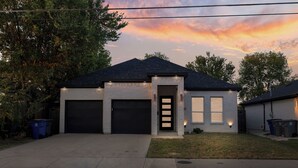 Ein modernes, zweistöckiges Haus mit Garage, einem gepflegten Rasen und einem Sonnenuntergangshimmel.
