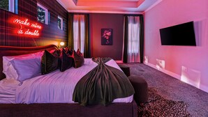 Ein modernes Hotelzimmer mit einem großen Bett, einem Flachbildfernseher und einem Neonzeichen.